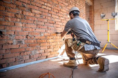 trabalhador-manual-em-um-canteiro-de-obras-no-processo-de-perfuracao-de-uma-parede-com-um-perfurador